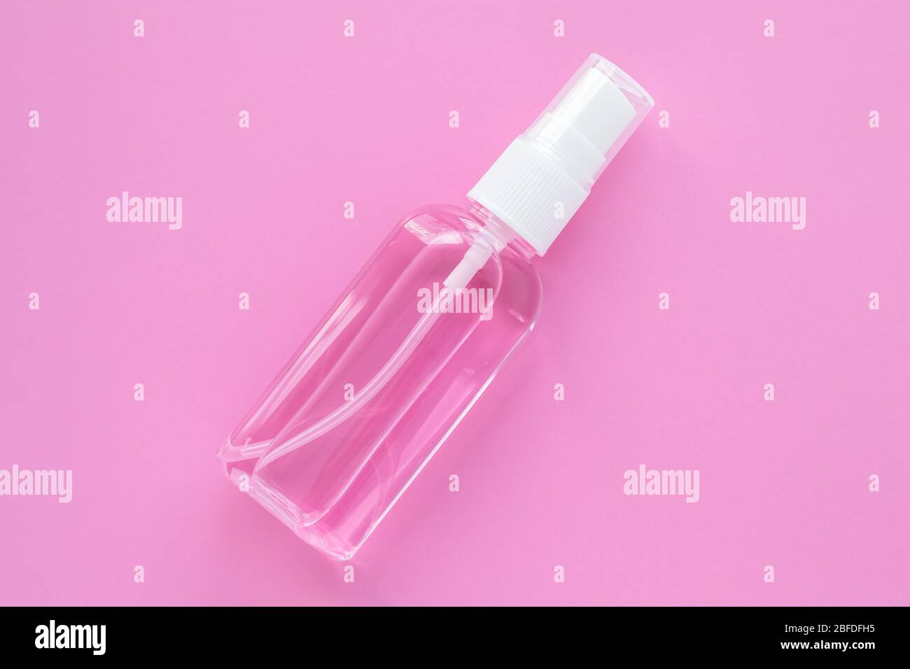Cosmetic bottle with hand sanitizer, antiseptic spray for disinfection. Remover liquid in container on a pink background. Cleanser product Stock Photo