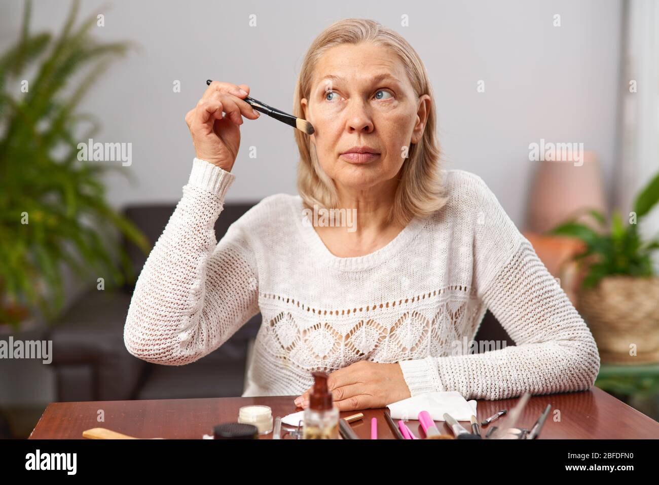 beautiful senior woman after applying make up holding a brush Stock Photo