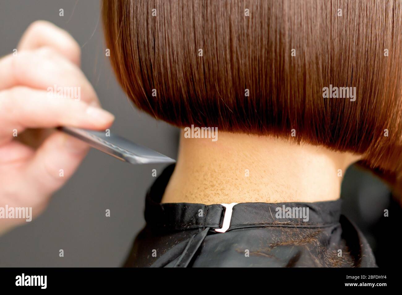 Hairdresser combs short hair of brunette woman close up in hair salon.  Toned Stock Photo - Alamy