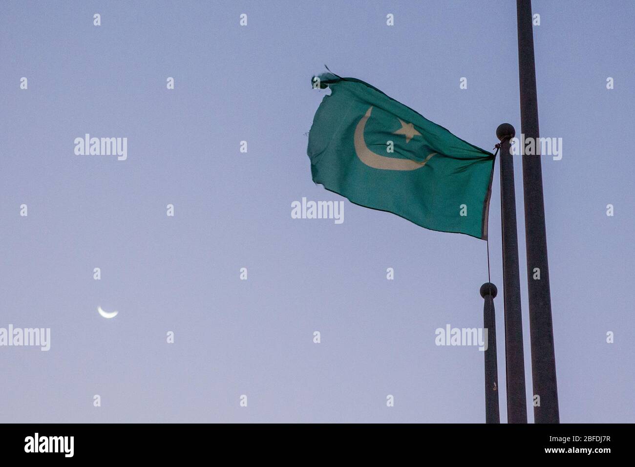 Crescent moon flag flying as a crescent moon rises. Stock Photo