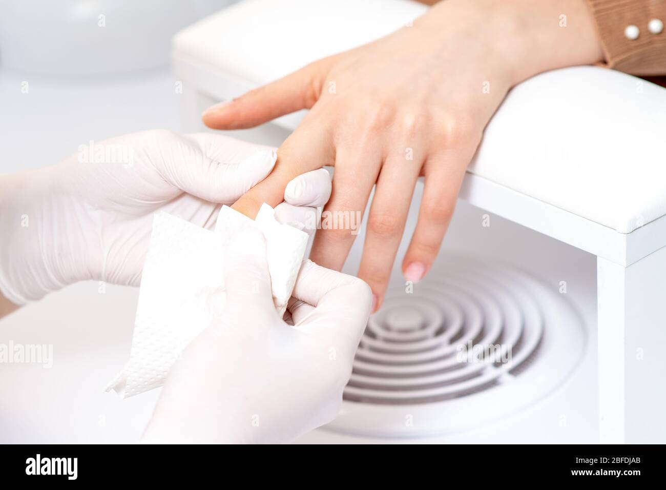 Manicure master hands are wiping the nails with a paper napkin in salon. Stock Photo