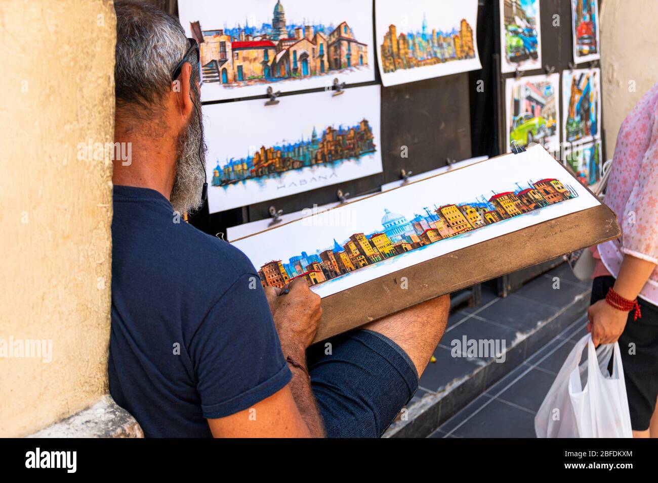 Havana, Cuba - 25 July 2018: Man relaxing while painting and selling paintings on a street in Old Havana Cuba. Stock Photo