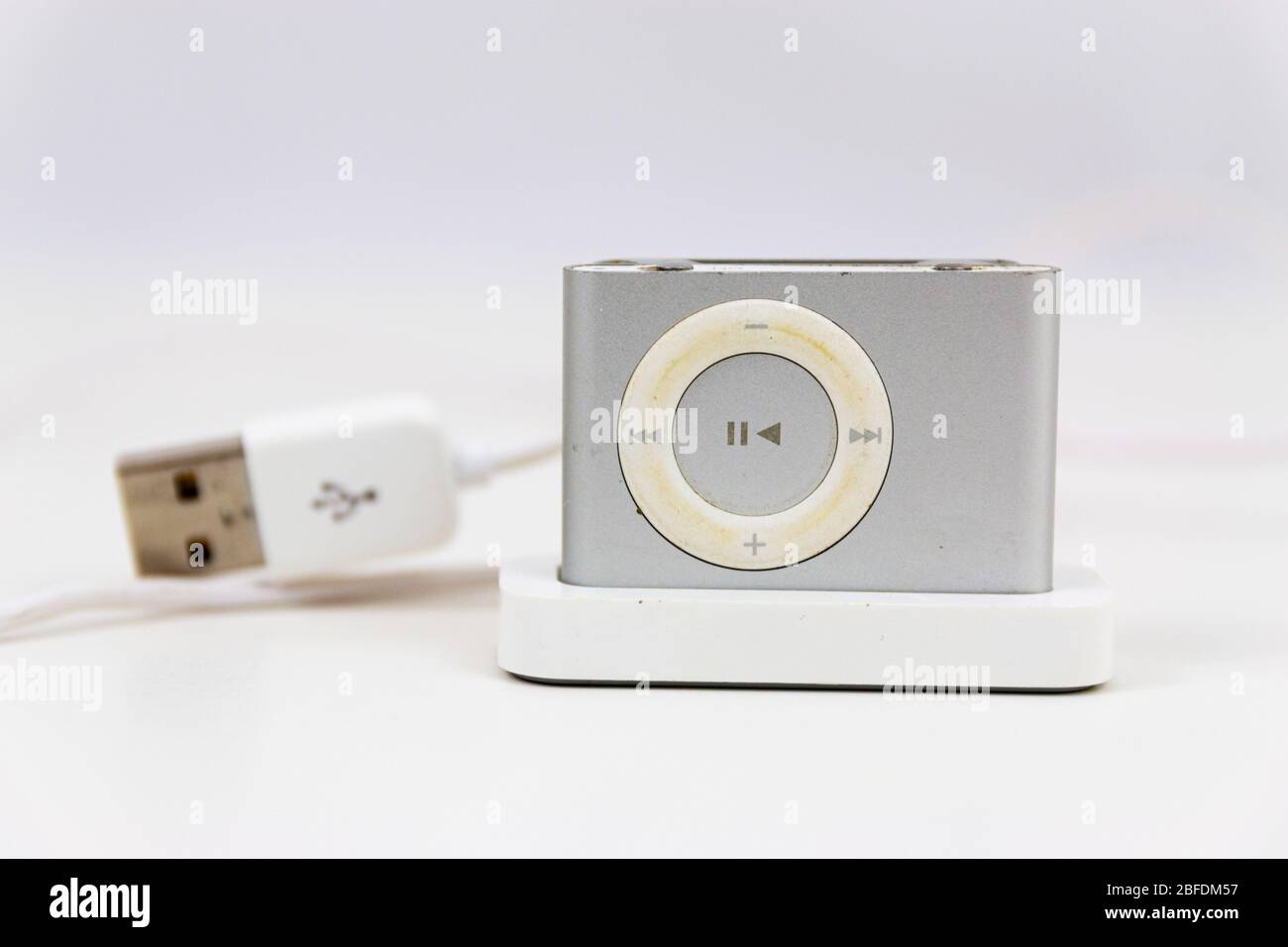 Babylon, New York, USA - 20 February 2020: A vintage mini mp3 digital music player in its charging stand with a white background and a usb cable. Stock Photo