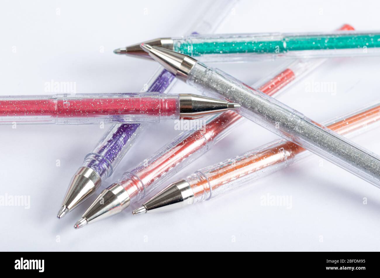 A selection of coloured glitter gel pens on a white backgroound Stock Photo