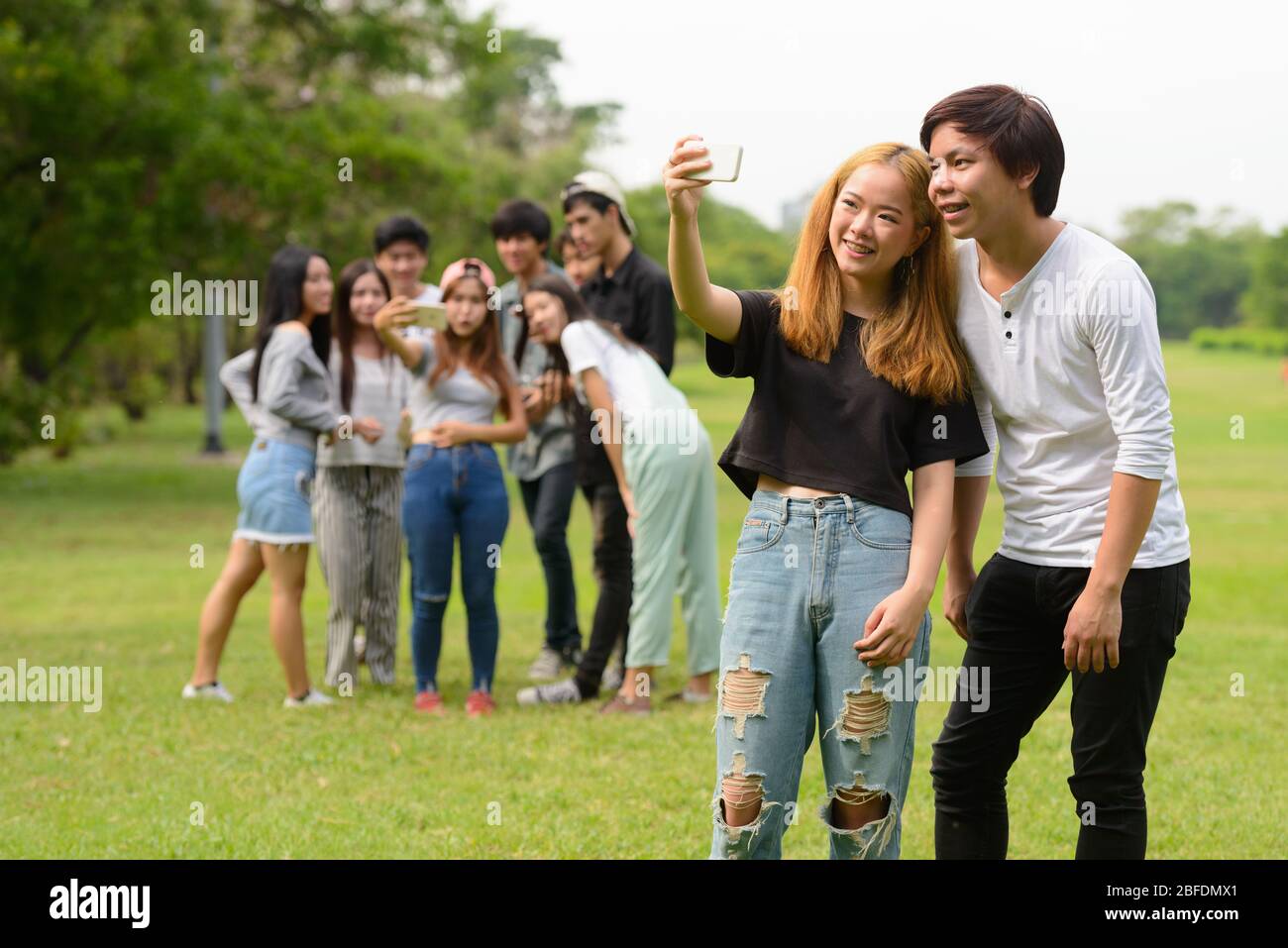 Happy young Asian couple taking selfie together with friends at the ...