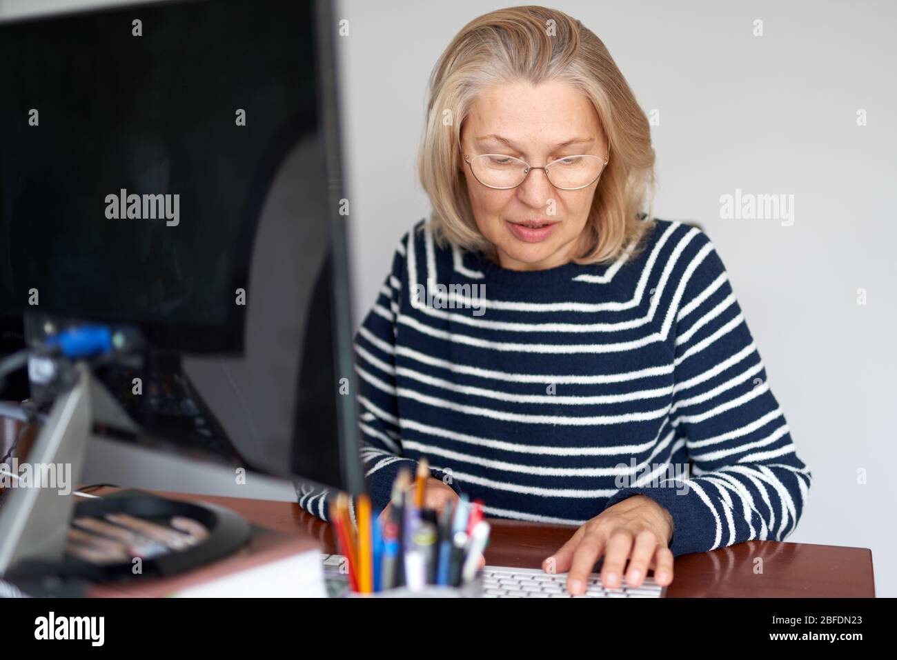 Woman in glasses using laptop typing email working at home office, lady ...