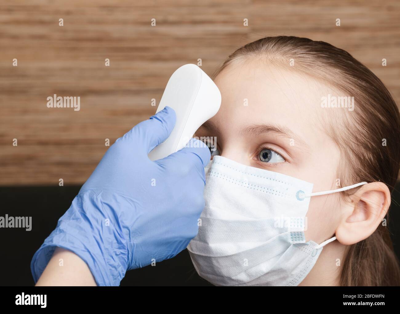 Pediatrician or doctor checks little girl's body temperature using