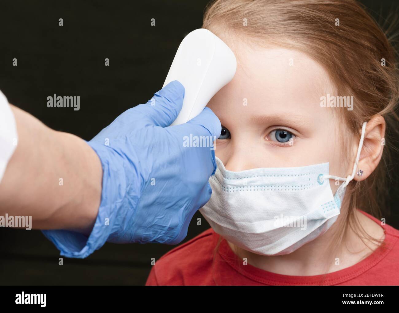 Pediatrician or doctor checks little girl's body temperature using