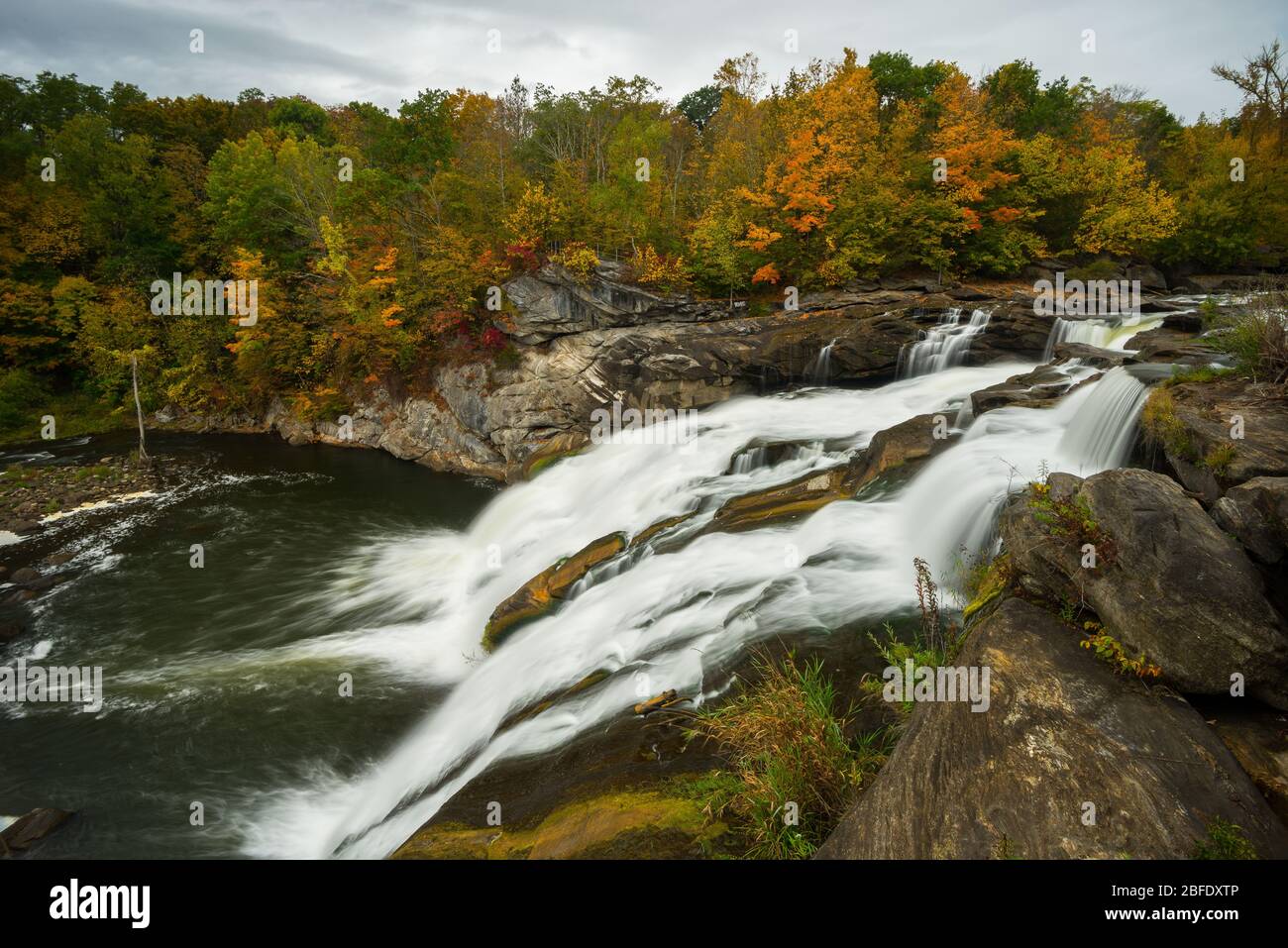 The waters of the Housatonic River furiously cascade over Great Falls amidst autumn woodlands (Canaan, Connecticut). Stock Photo