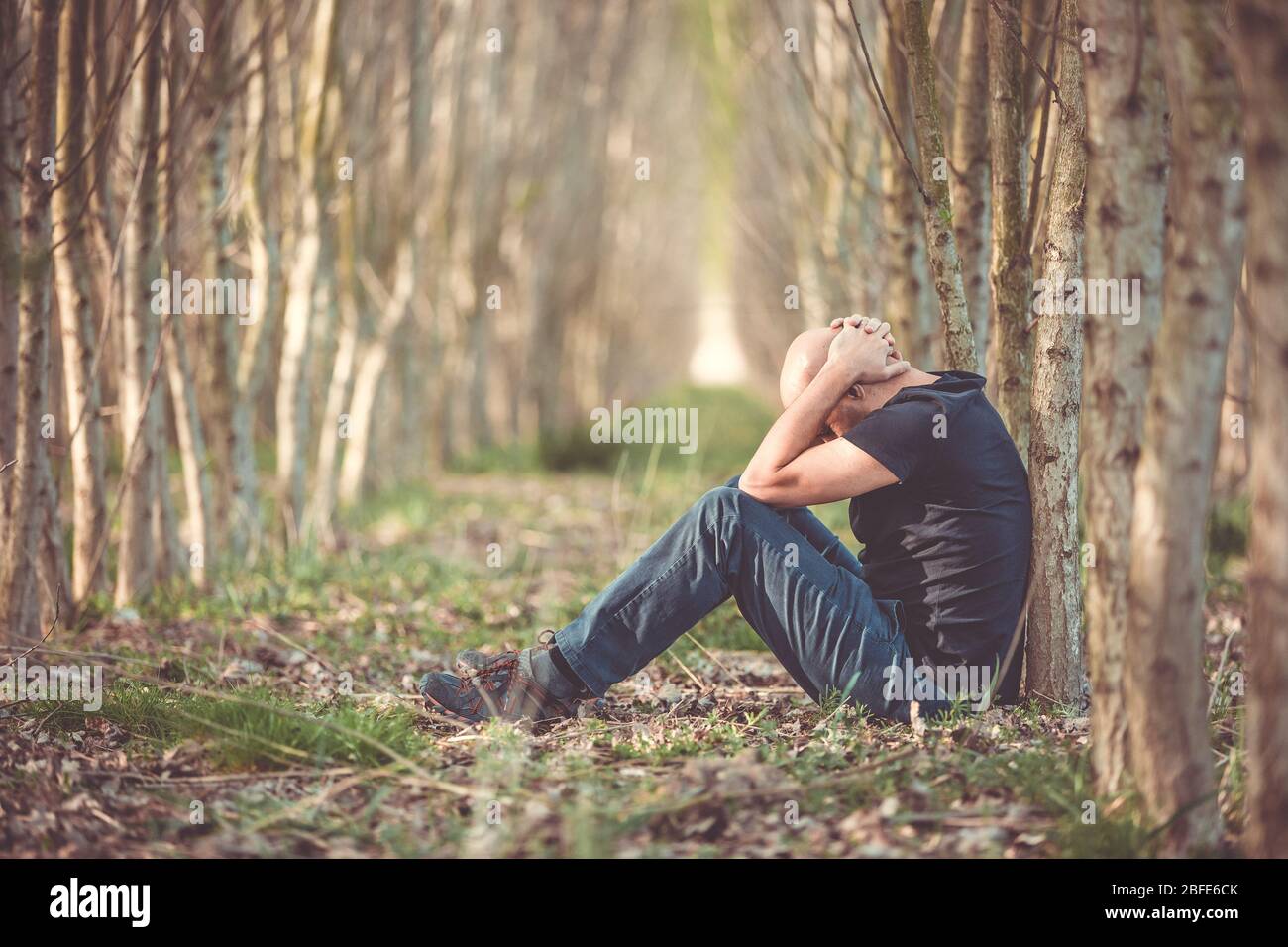 Sitting man with depression going through a rough patch in his life, suffering from mental exhaustion, anxiety, burnout Stock Photo