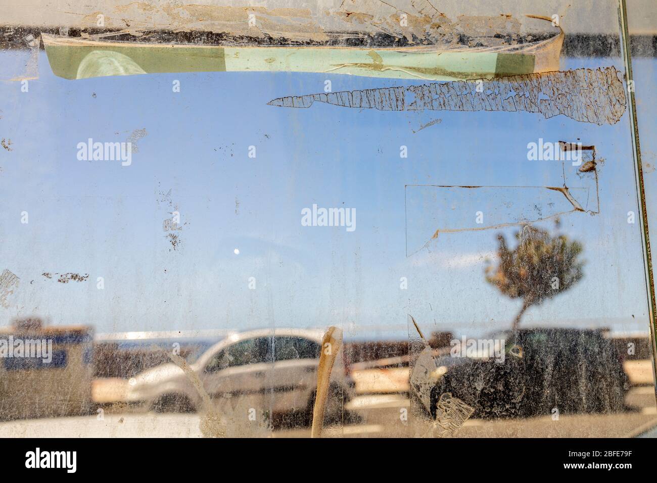 Dirty textured glass on an old bus shelter between camera and the seafront, coronavirus pandemic, Playa San Juan, Tenerife, Canary Islands, Stock Photo