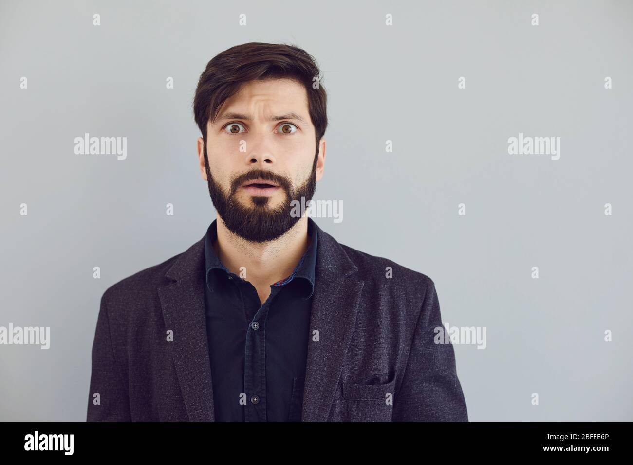 Puzzled insecure man in casual jacket on a gray background. Expression of emotion Stock Photo