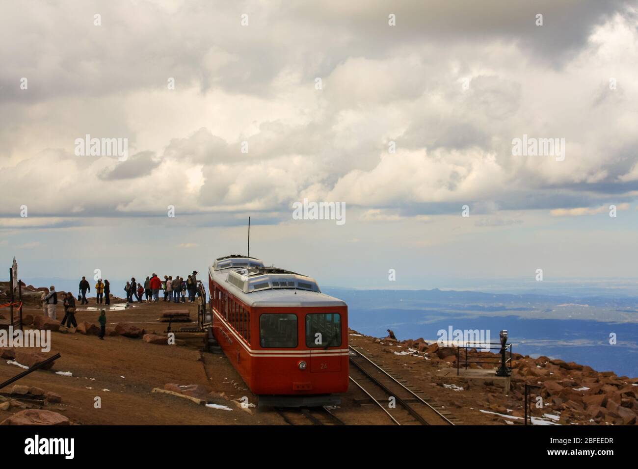 Cog railway carriage at summit of Pikes Peak in Rocky Mountains with tourists sightseeing queuing to board red train. Colorado USA Stock Photo