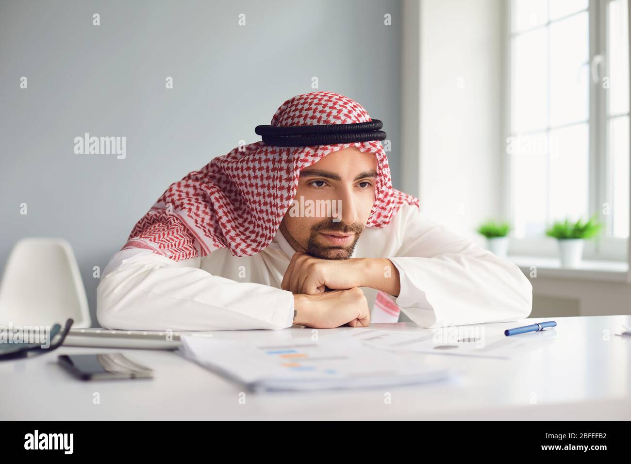 Calm arab man looking sitting at a table in an office room Stock Photo