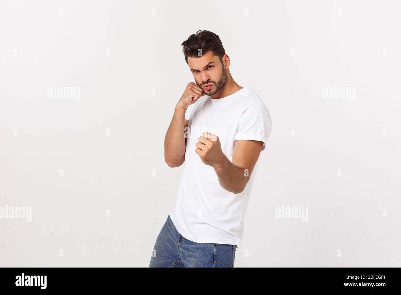 Young handsome man over isolated background Punching fist to fight, aggressive and angry attack, threat and violence Stock Photo