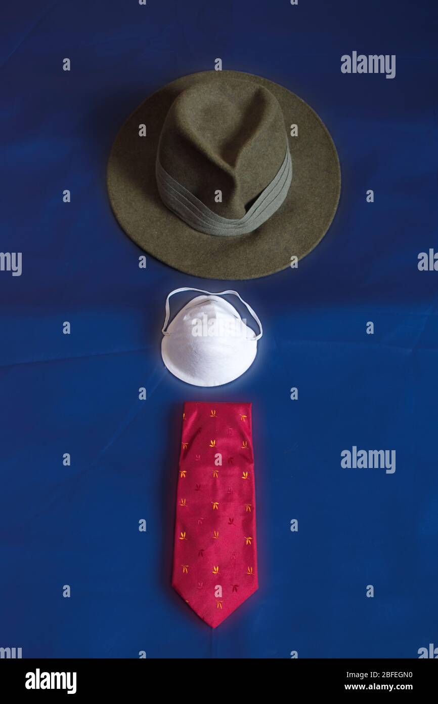 A green felt hat, a tie and a face mask are spread out on a blue fabric. Stock Photo