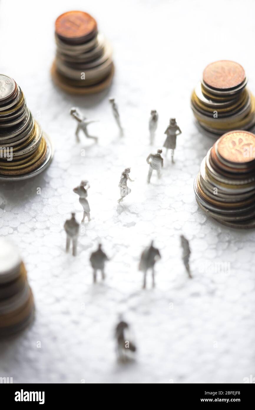 Tiny white plastic figures are forming a question mark among heaps of old European coins. Stock Photo