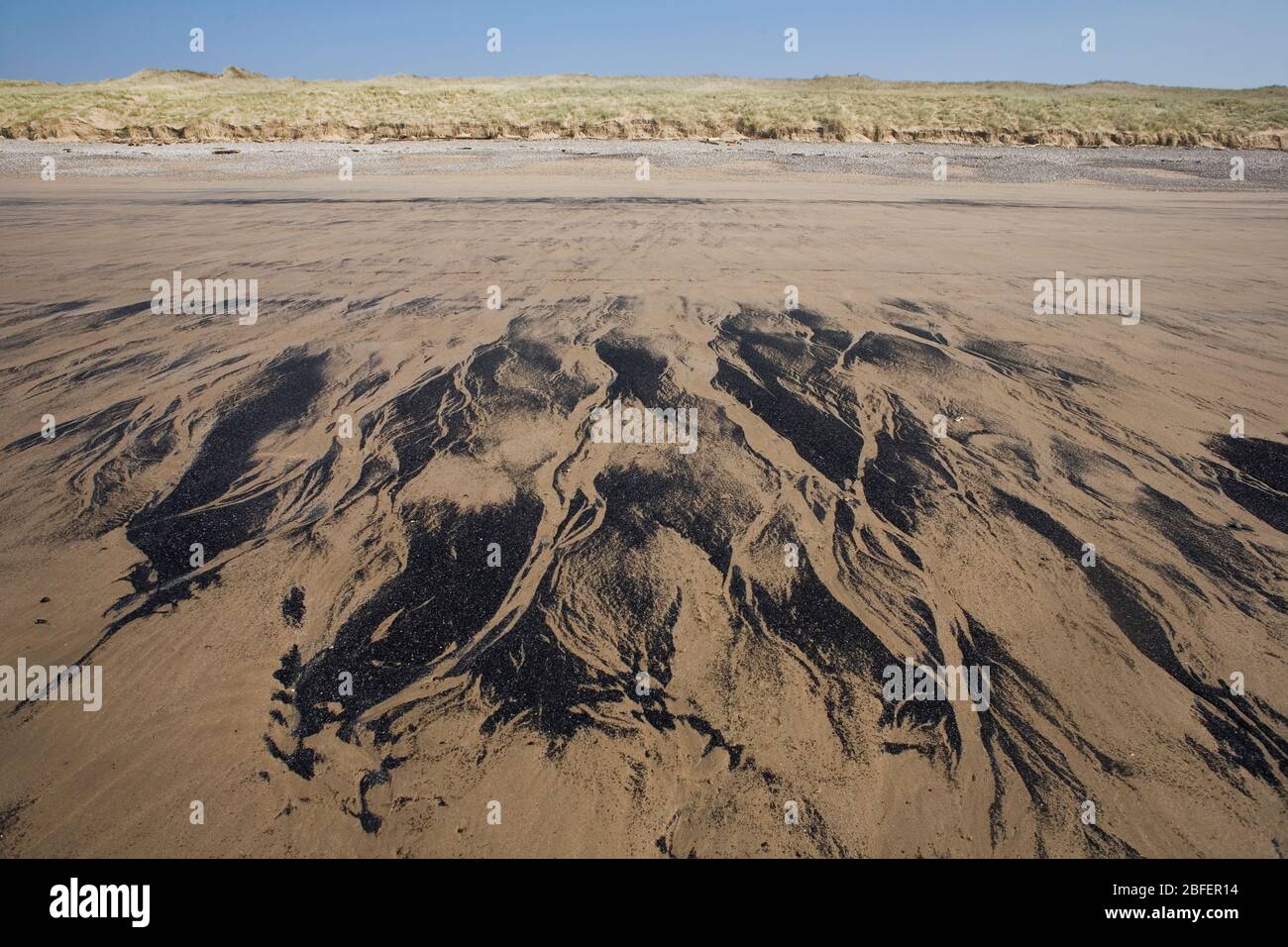 Pattern of fine black residue on sand on Newton Beach Porthcawl Stock