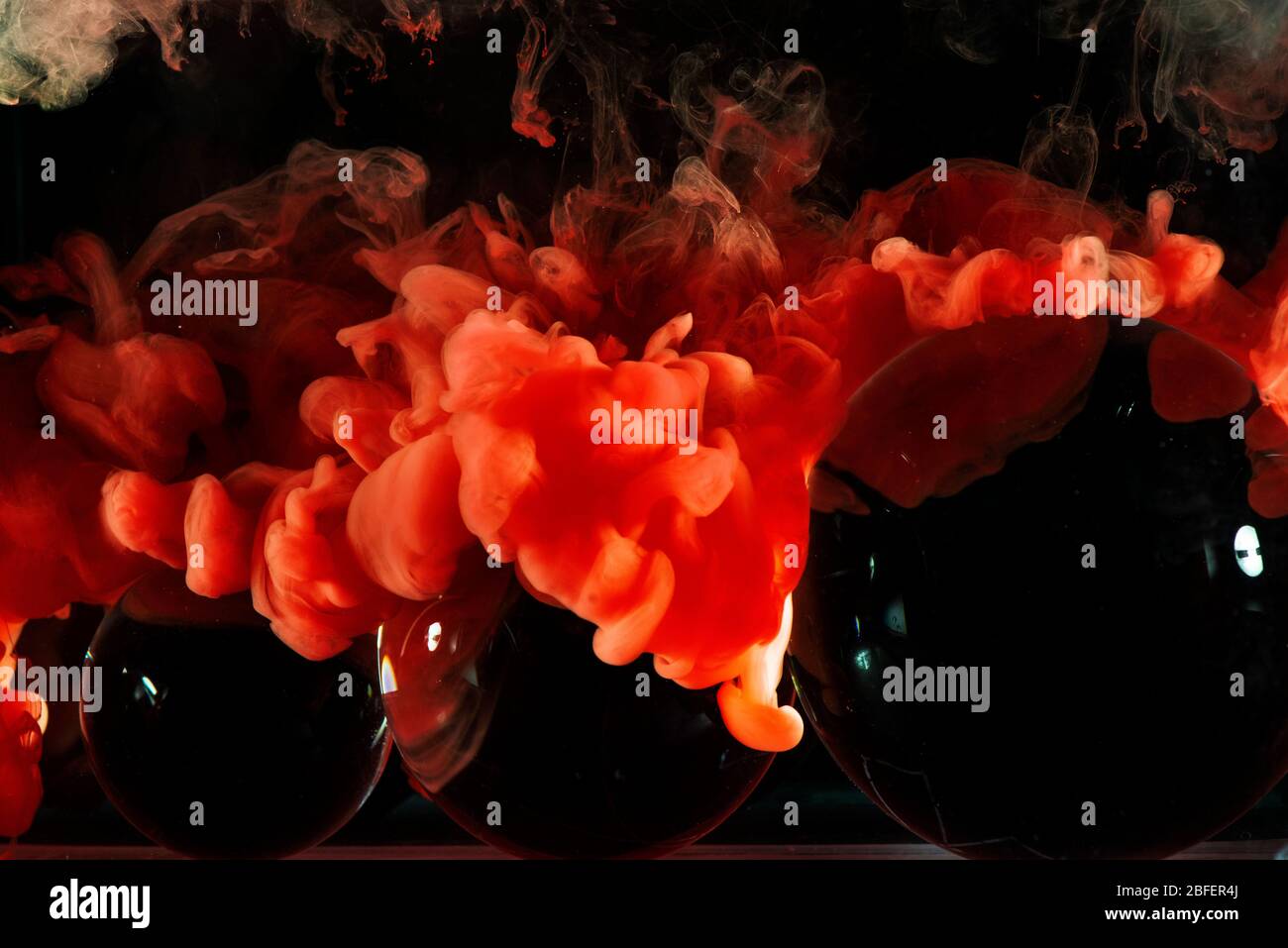 Three Glass balls with blue paint splash underwater and on a black