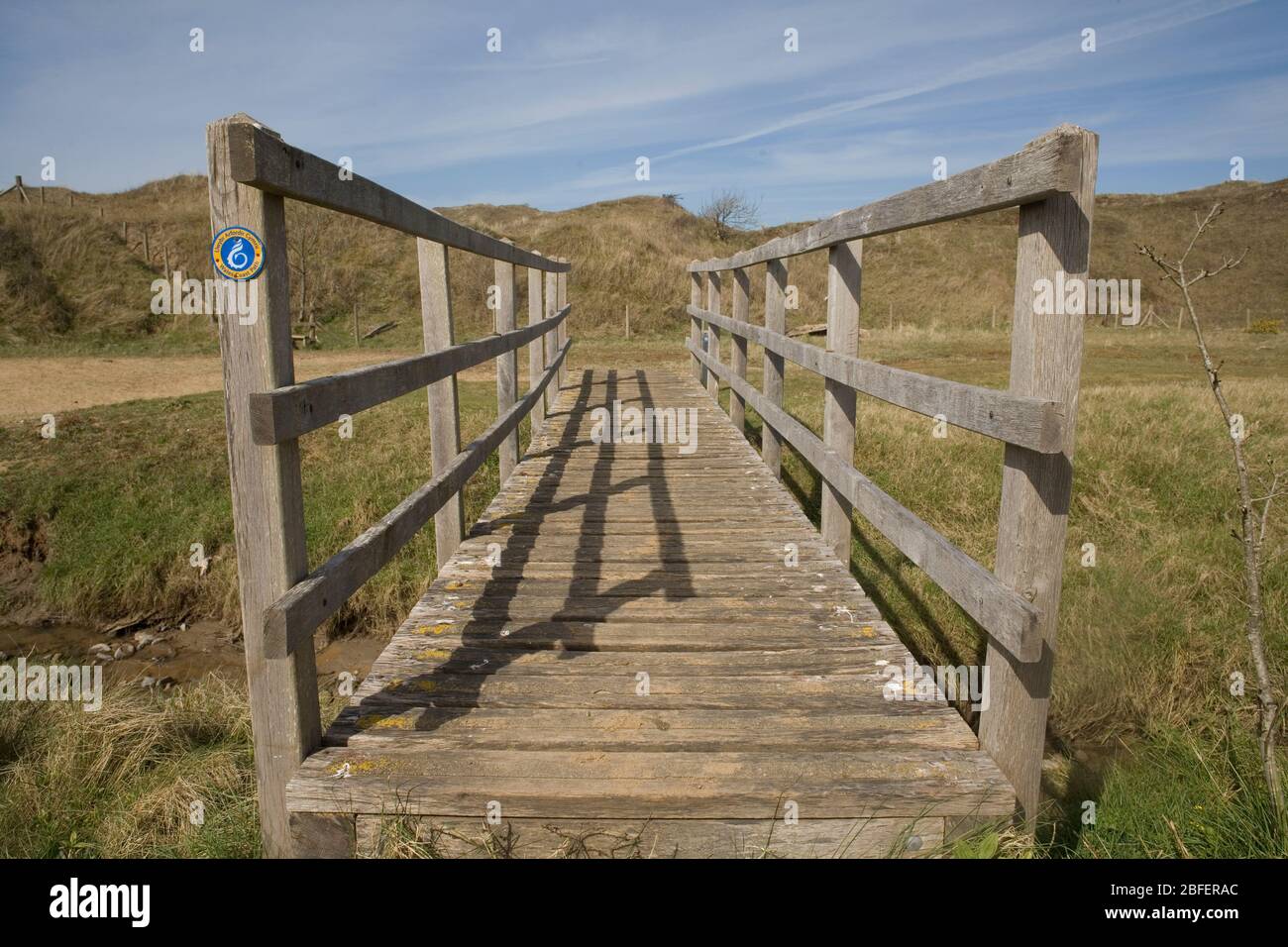 wooden footbridge taking Wales coast path over an inlet of the Ogmore river in Mertrhy Mawr nature reserve Stock Photo