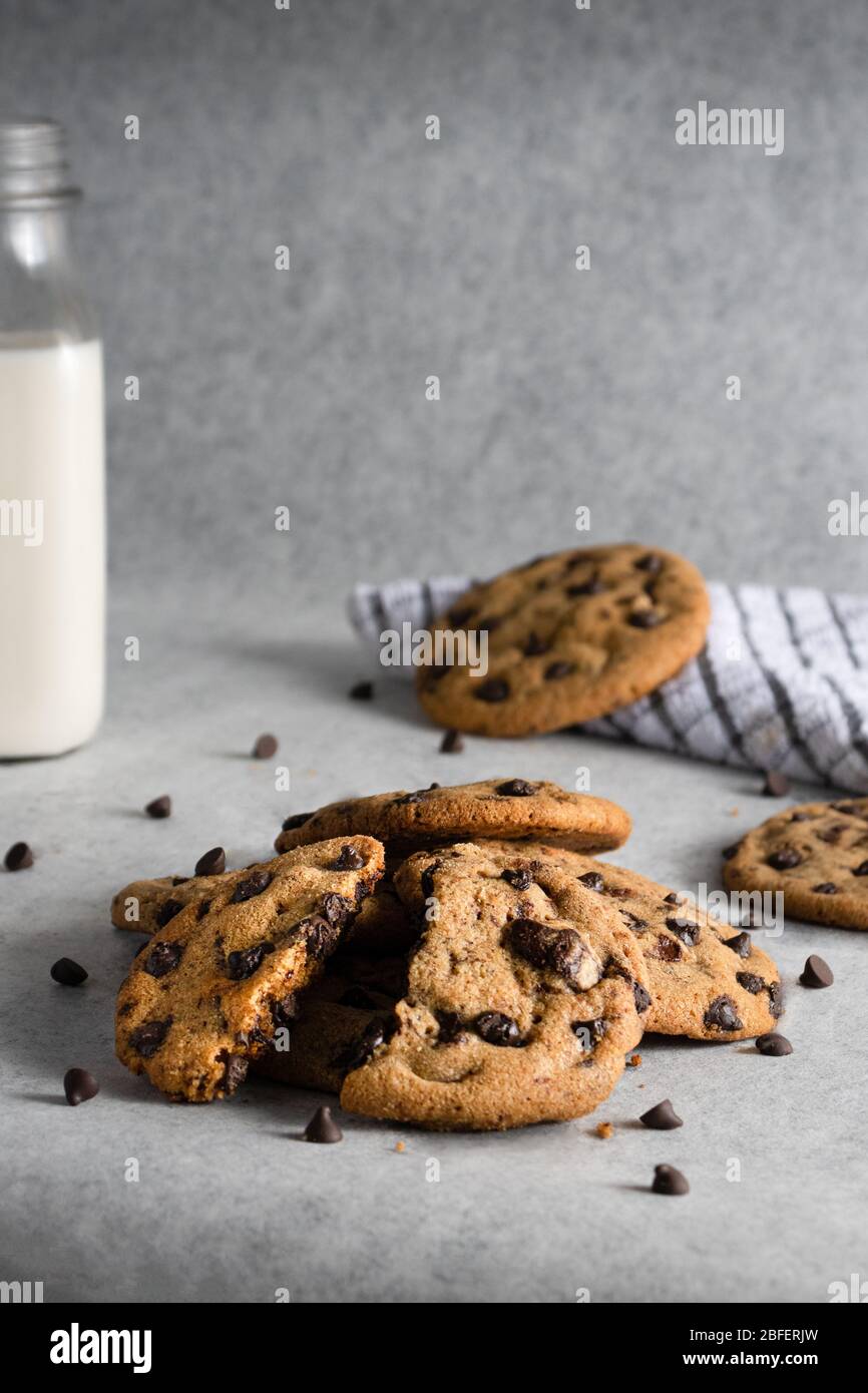 chocolate chip cookies in the foreground with a bottle of milk in the background Stock Photo