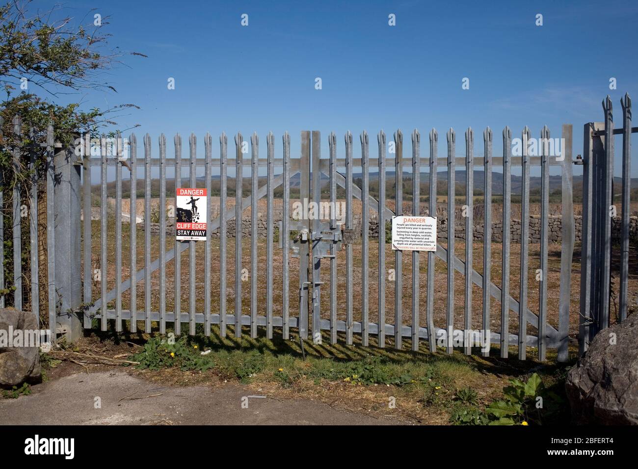 Padlocked metal fence and warning notices at Cornelly quarry Stock Photo