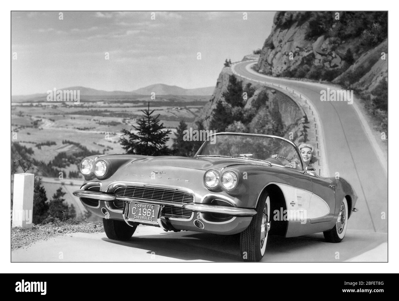 Chevrolet Corvette 1961 open top 2 seater sports car motorcar product image photograph with model in outdoor winding mountainous road lifestyle situation Stock Photo