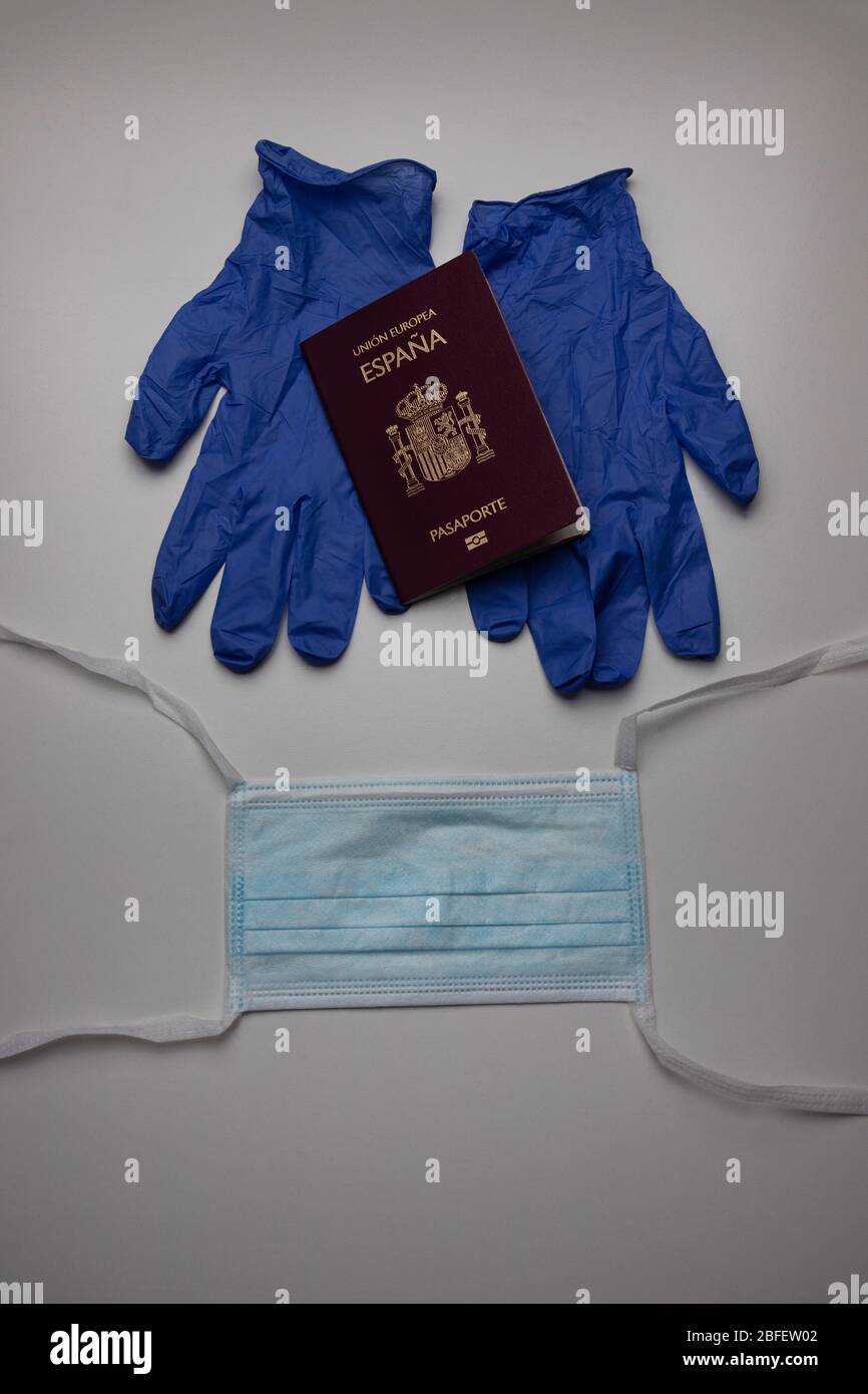 Gloves holding a Spanish, european union passport, and a face mask. Travel restrictions, quarantine, covid-19, new coronavirus pandemic prevention Stock Photo