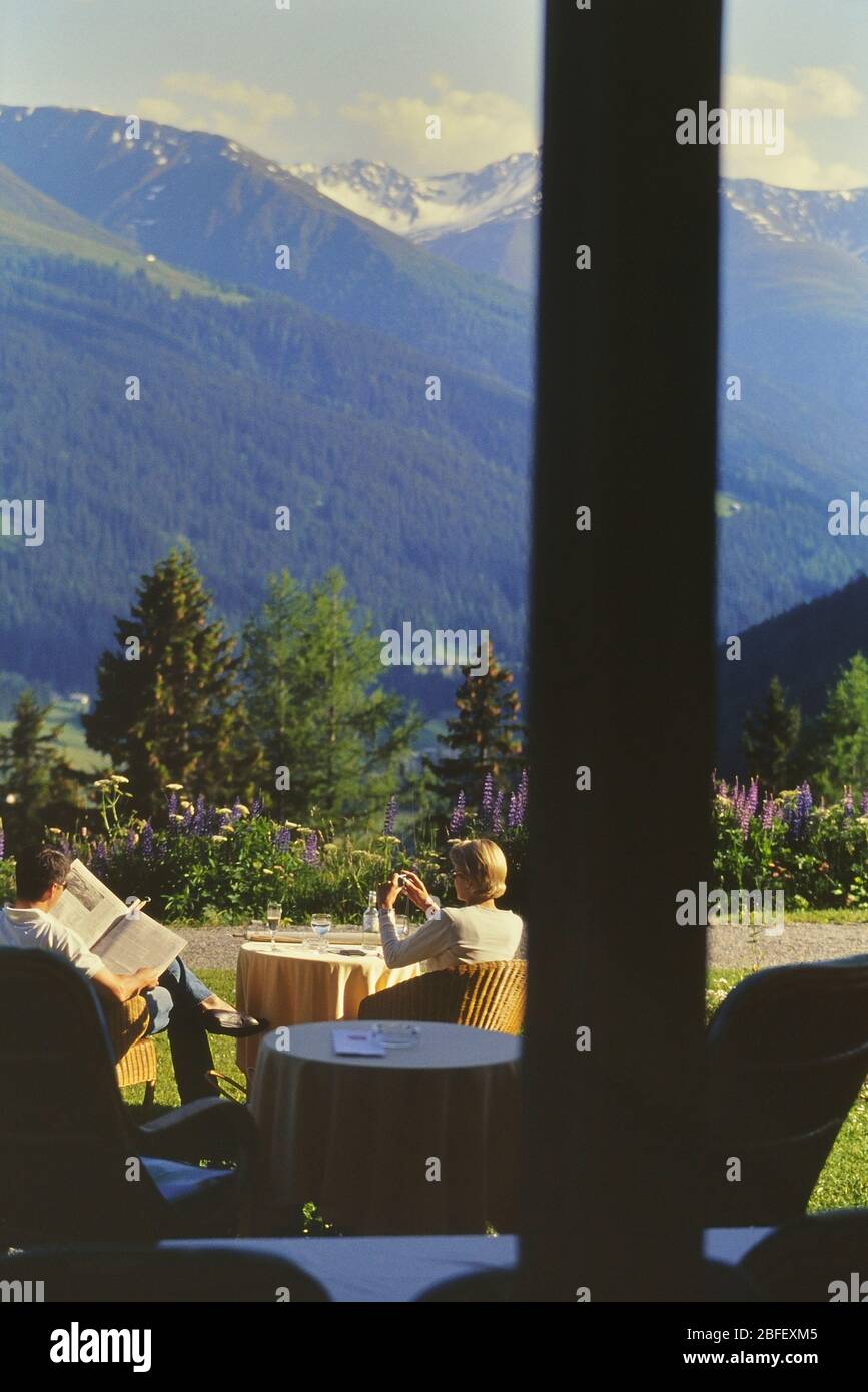 A couple relaxing on the mountain terrace, Berghotel Schatzalp, Davos, Switzerland, regarded as the inspiration for Thomas Mann’s The Magic Mountain. Stock Photo