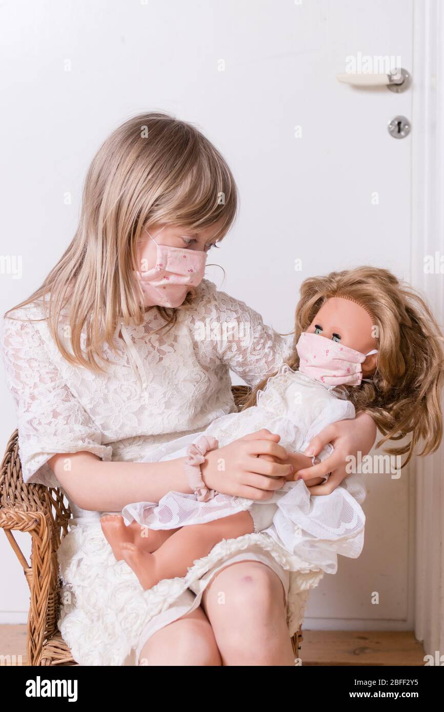 girl with homemade covid 19 protection mask with her doll Stock Photo