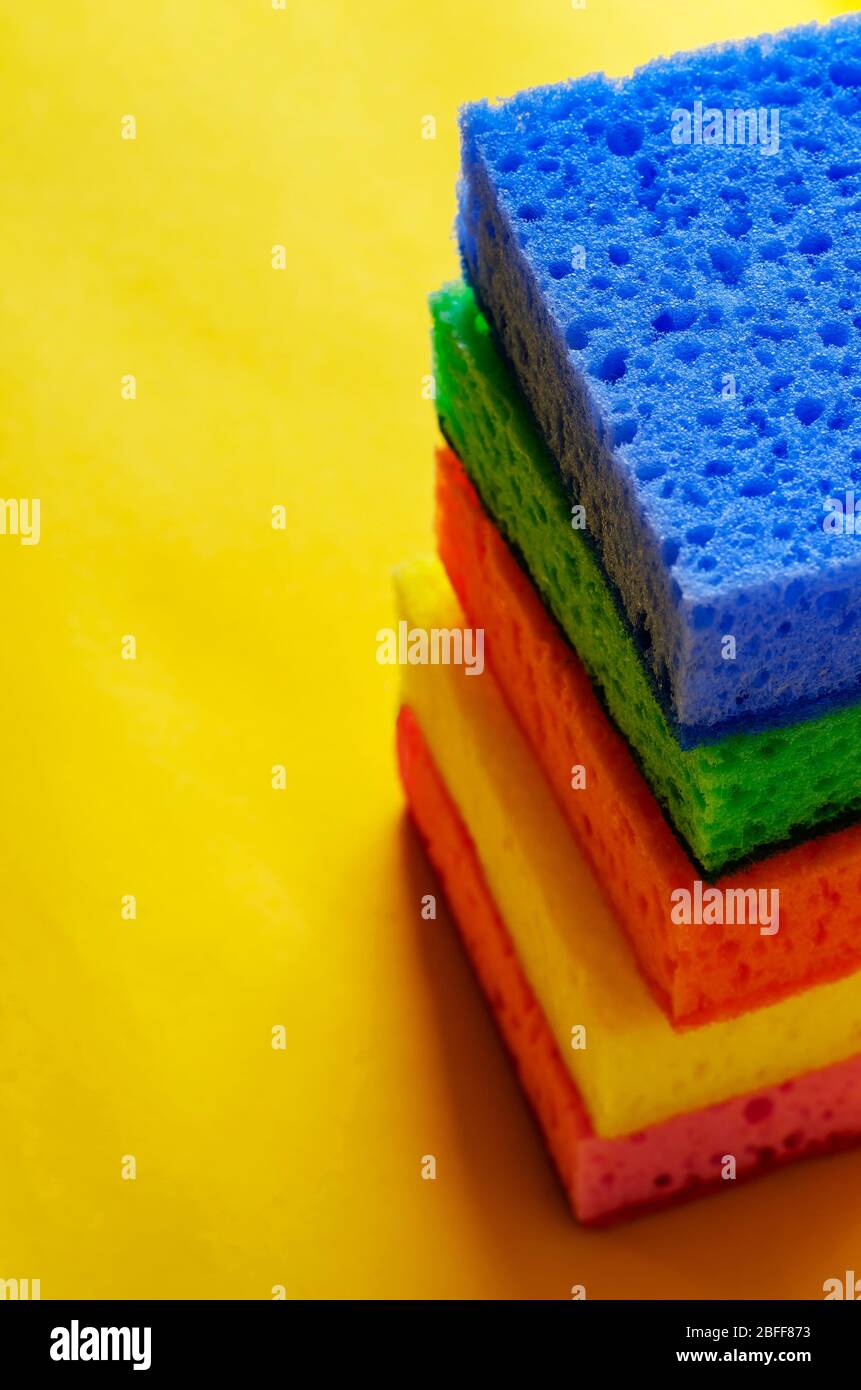 Kitchen porous sponges. A stack of multi-colored kitchen sponges on a yellow background. A set of new bright accessories for cleaning. Commercial clea Stock Photo