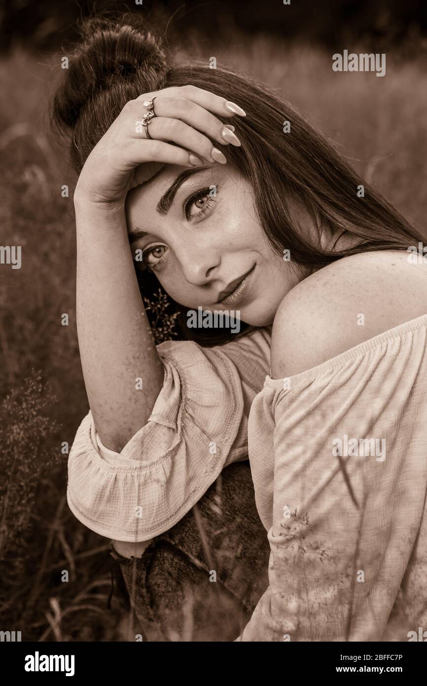 An attractive young woman frames her face with her lower arm and hand