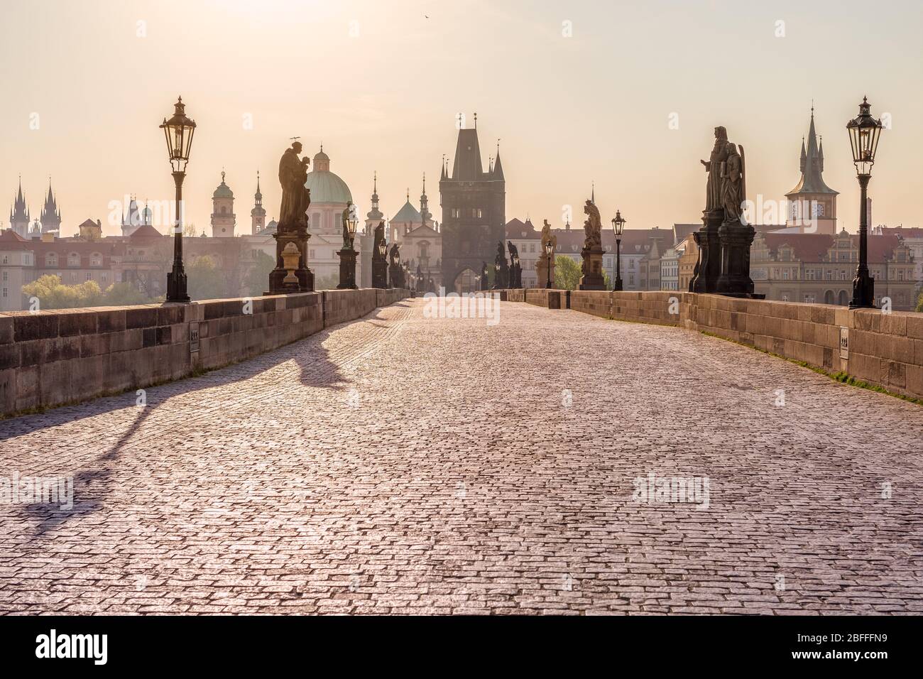 Medieval stone Charles bridge with statues of saints in a thin haze during sunrise, Prague, Czech Republic Stock Photo
