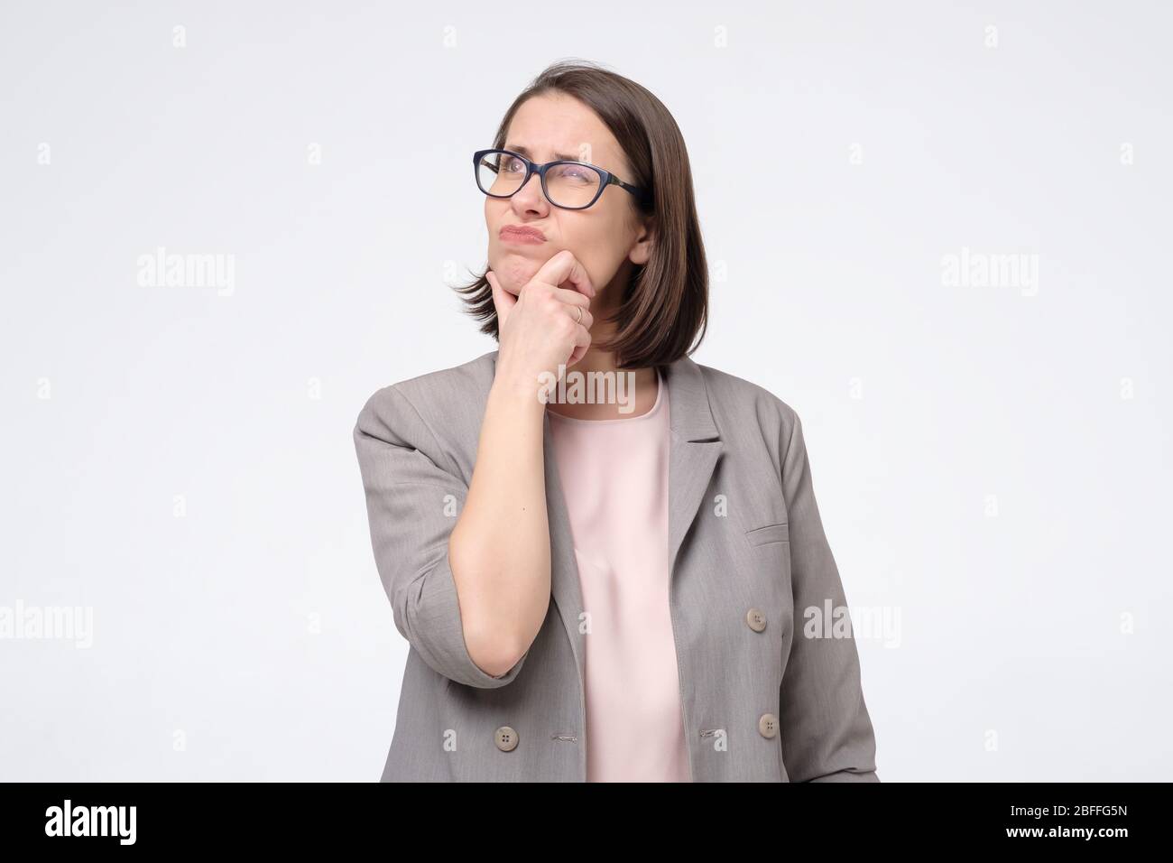 Pretty mature woman in glasses looking aside with thoughtful look making plan for tomorrow. Generating idea for business project. Studio shot Stock Photo