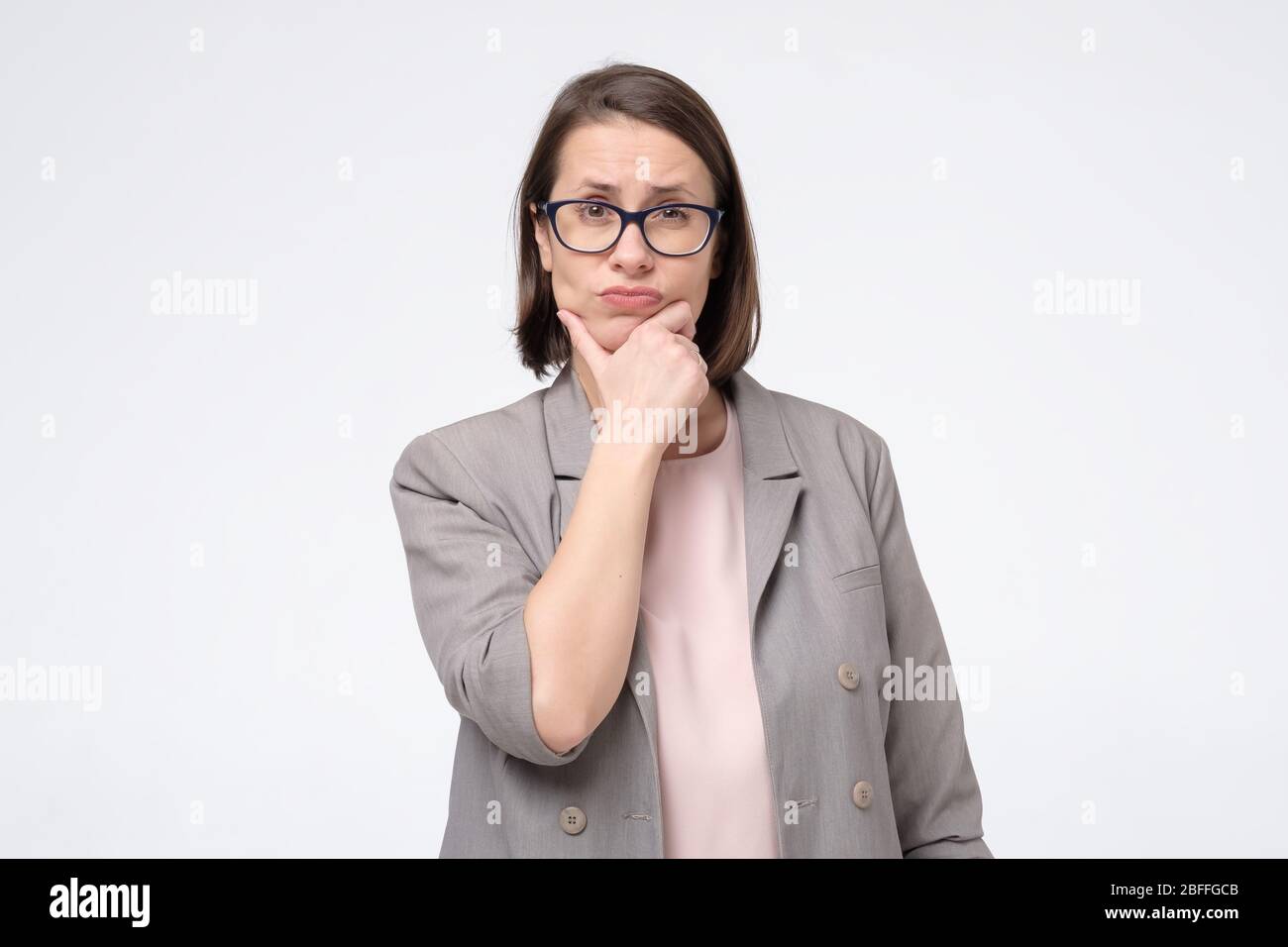 Pretty mature woman in glasses looking aside with thoughtful look making plan for tomorrow. Generating idea for business project. Studio shot Stock Photo