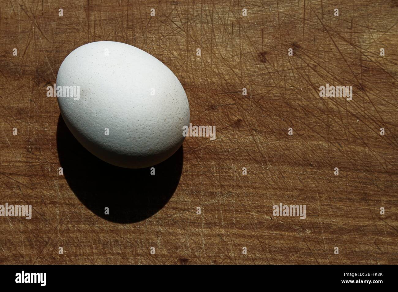 Single standing egg on wooden board. Hard life egg Stock Photo