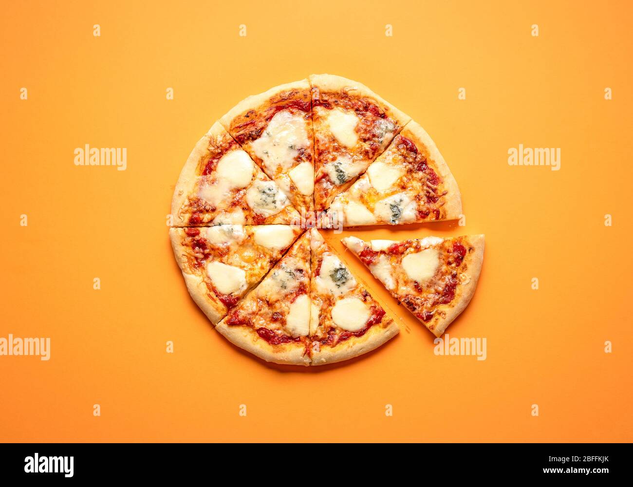 Sliced cheese pizza on an orange background above view. Pizza sliced in