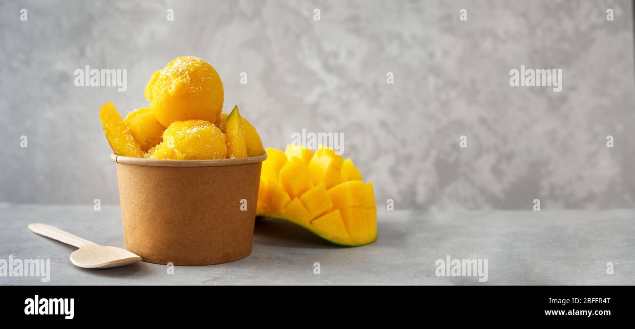 Refreshing mango ice cream in craft paper cup on gray background Stock Photo