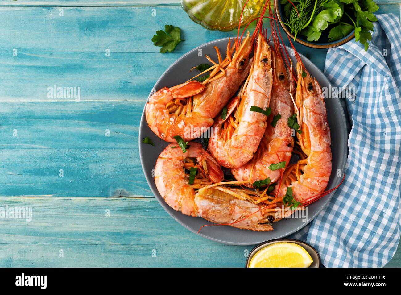 Top view of turquoise color dining table with cooked red prawns and ingredients Stock Photo
