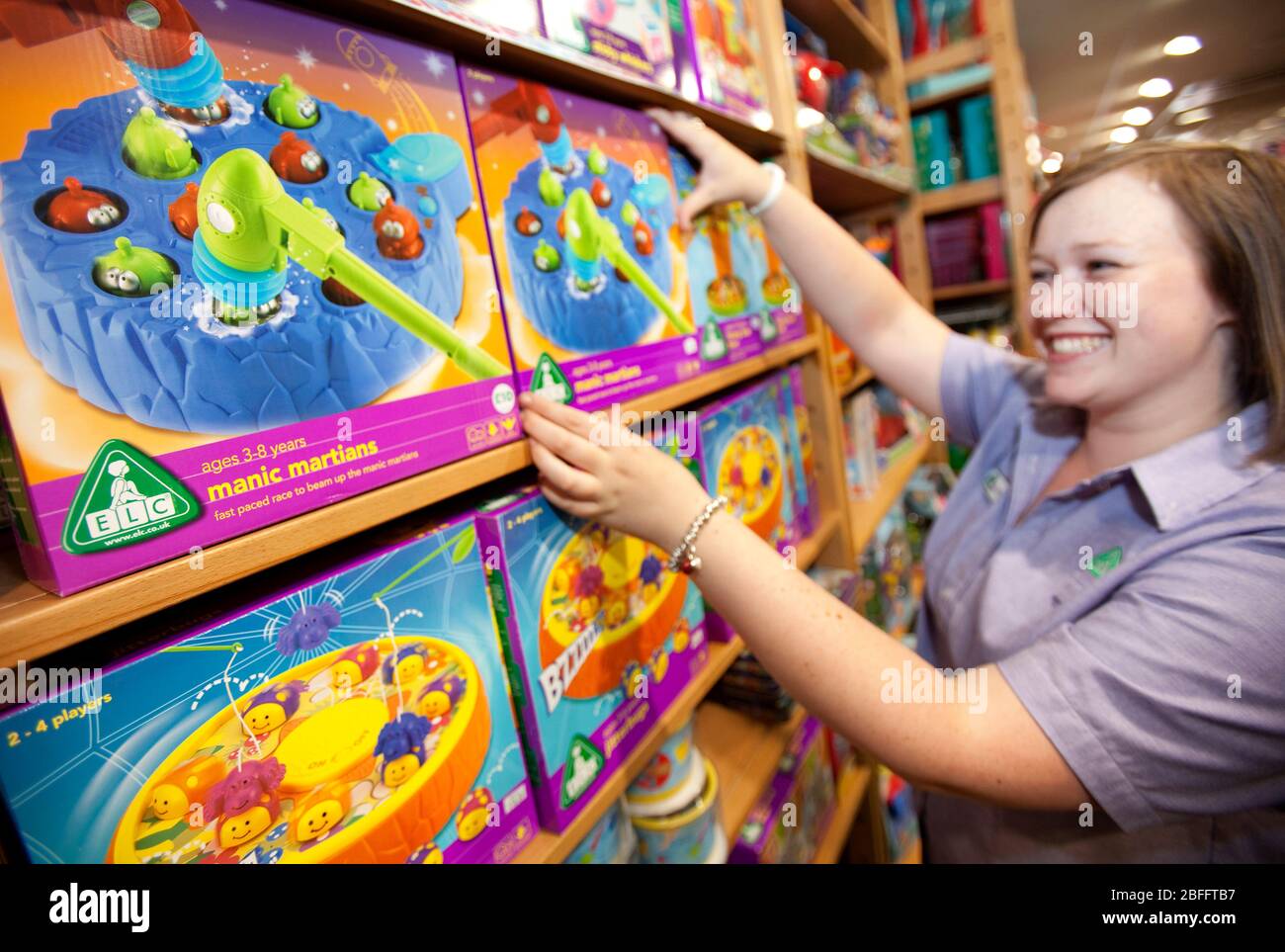 An Early Learning Centre employee tidies shelves on the shop floor, Kensington, London Stock Photo