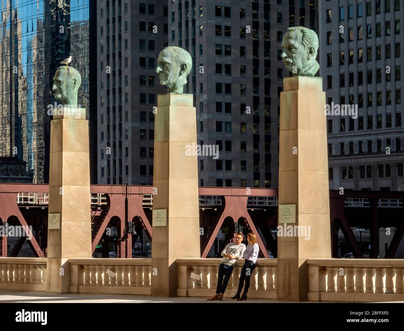 Portrait statues of famous businessmen Robert Wood, Julius Rosenwald and Frank Winfield Woolworth stand on columns before Chicago's Merchandise Mart on the Chicago River. Stock Photo