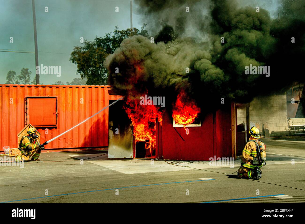 Firemen spray water on a burning model living room in a fire department structural firefighting demonstration in Costa Mesa, CA. Stock Photo