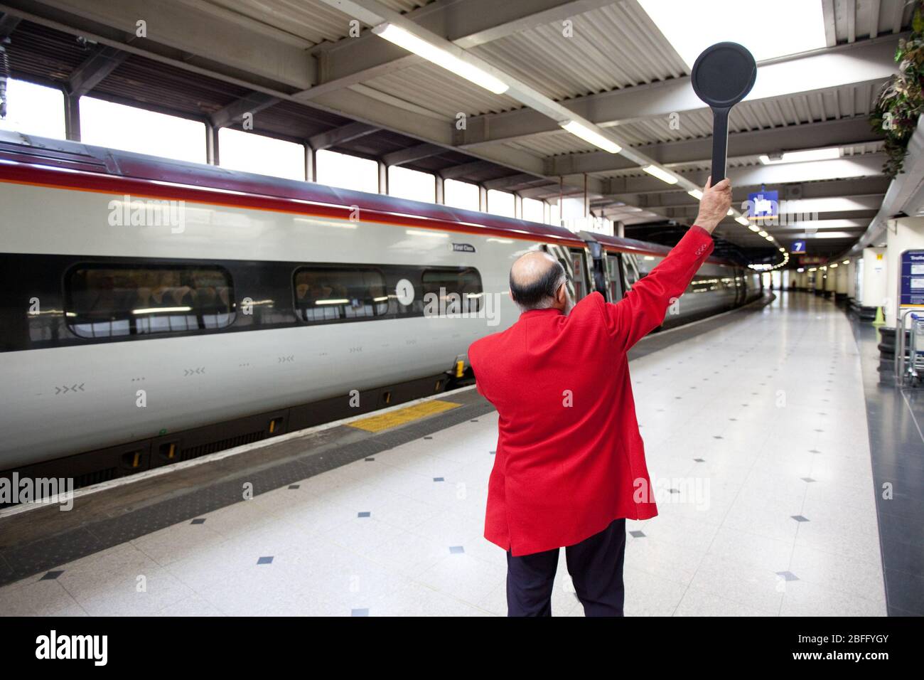 A Virgin Train's employee at London's Euston station signals a train is