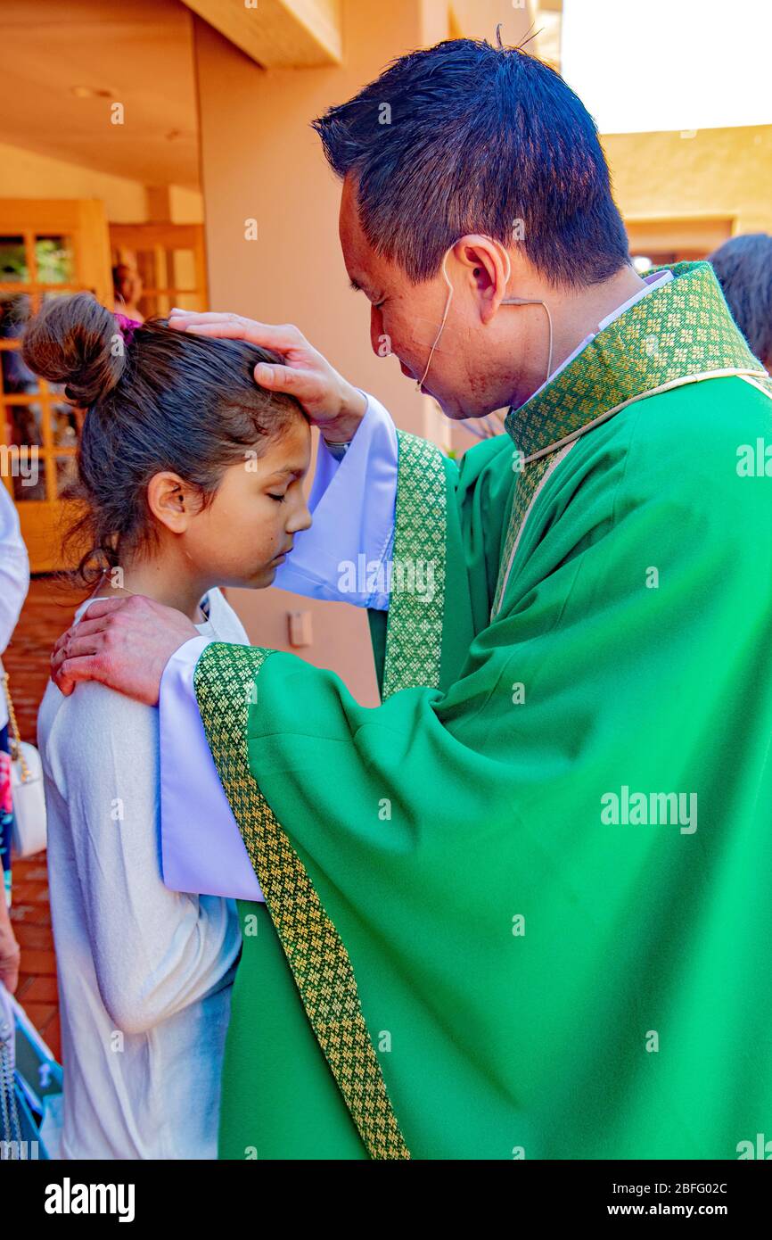 A robed Vietnamese American priest blesses a young parishioner after mass at a Southern California Catholic church. Stock Photo