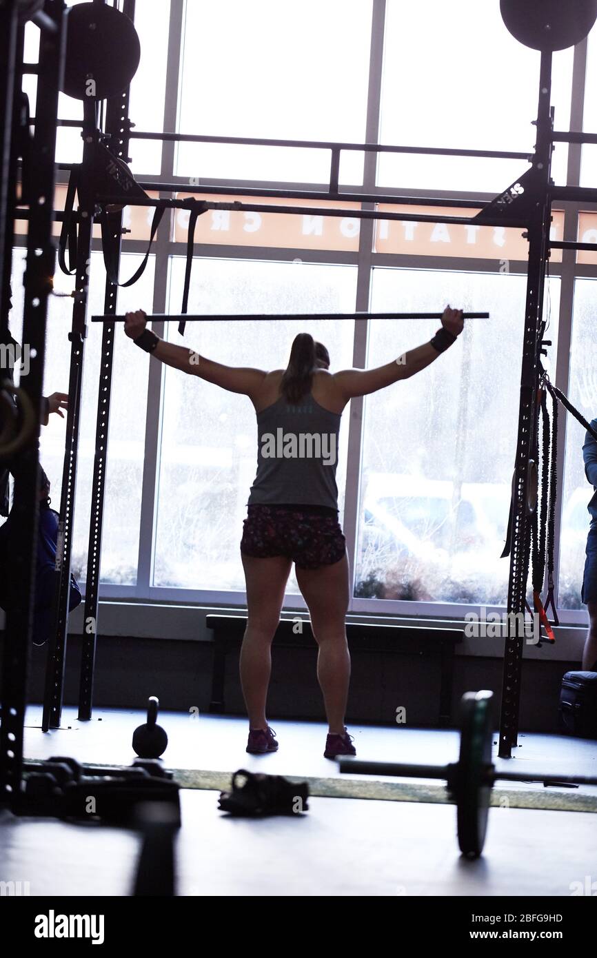 A silhouette of a Crossfit female athlete stretches between workouts Stock Photo