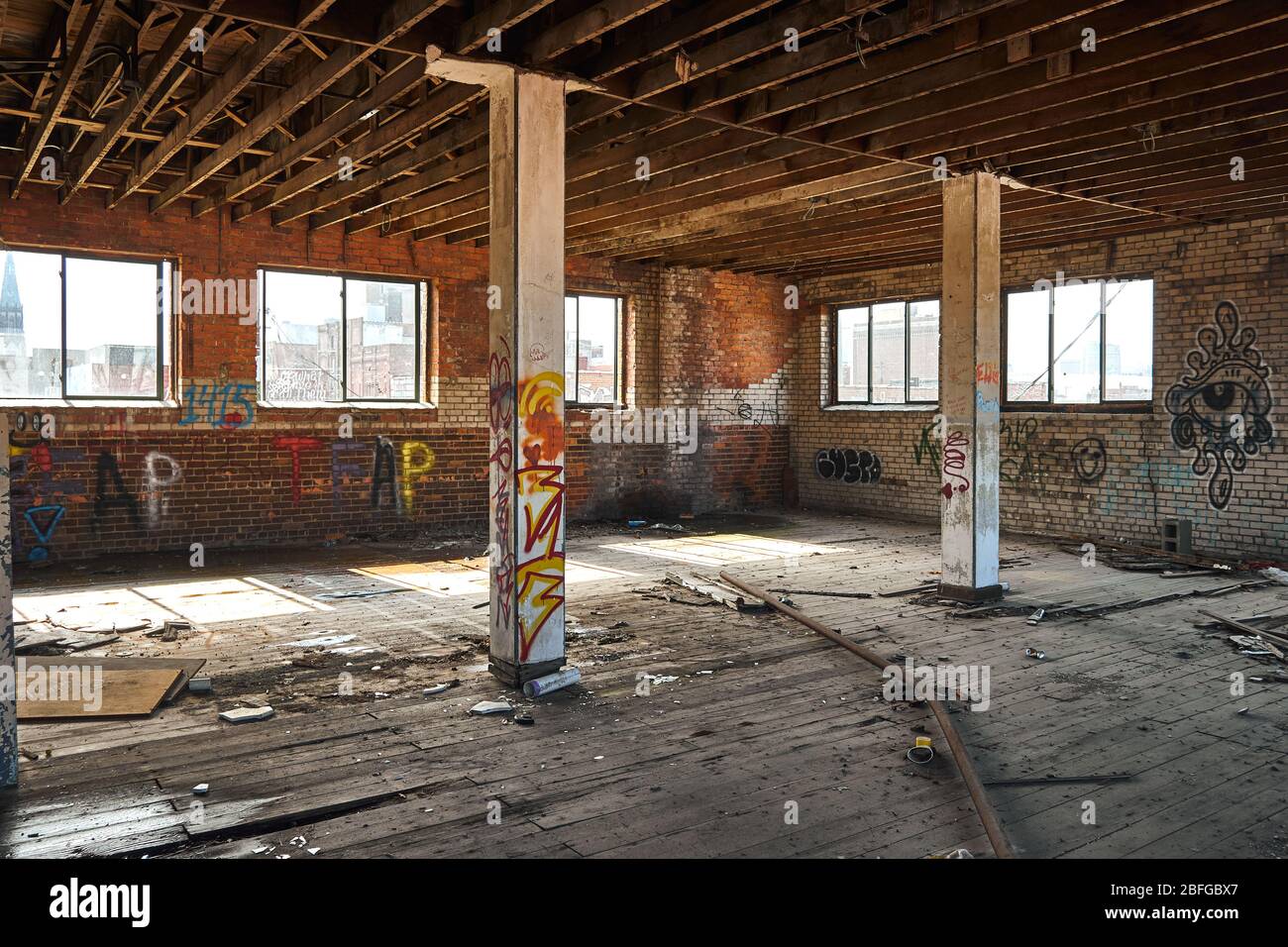 Photograph of interior of abandoned building in Detroit Michigan showing evidence of homeless and graffiti spray painted on walls Stock Photo