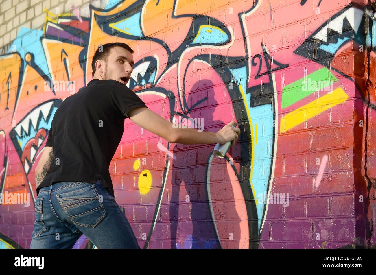 Young Graffiti Artist With Backpack And Gas Mask On His Neck Paints Colorful Graffiti In Pink Tones On Brick Wall Street Art And Contemporary Paintin Stock Photo Alamy