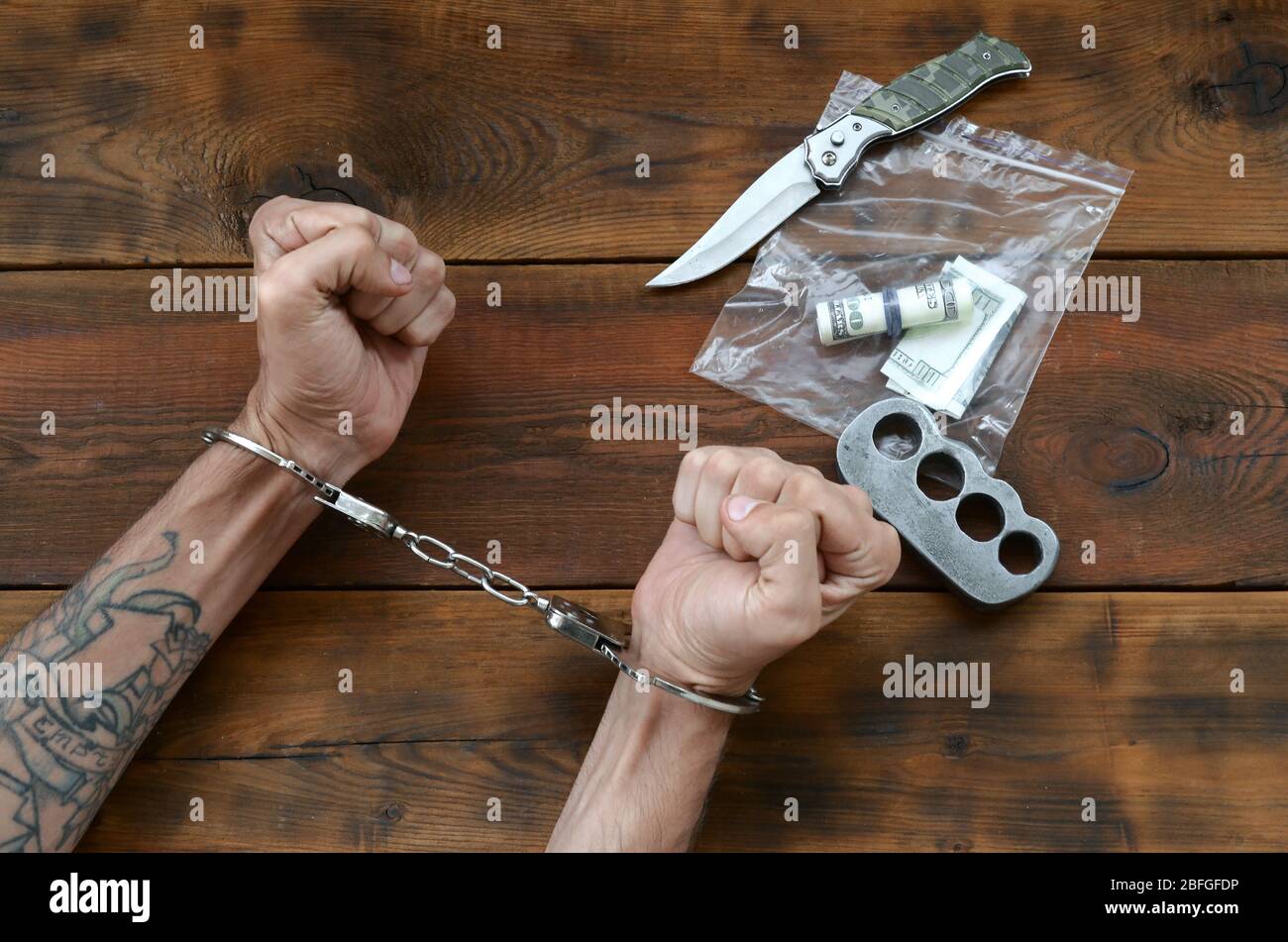 Cuffed hands of tattooed criminal suspect and plastic ziplock packet of evidence for investigation. Dirty money bills with jackknife and brass knuckle Stock Photo - Alamy Cuffed hands of tattooed criminal suspect and plastic ziplock packet of evidence for investigation. Dirty money bills with jackknife and brass knuckle Stock Photo - Alamy