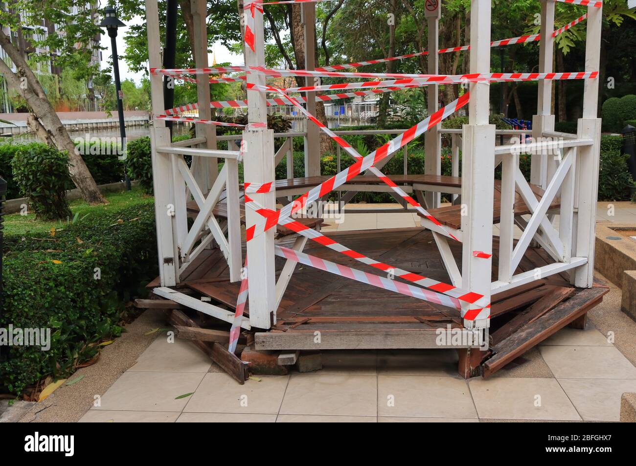 Closeup and focus on barricade tape surrounding the wooden pavilion, people cannot gather, they have to keep social distancing due to coronavirus Stock Photo