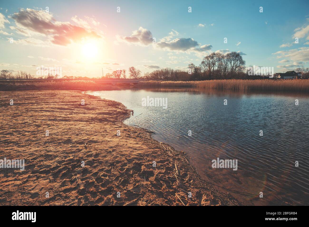 View of the river on the meadow in evening at sunset light. Beautiful nature landscape with the bright evening sky Stock Photo